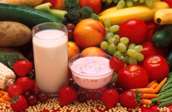 Cup of milk surrounded by various fruits